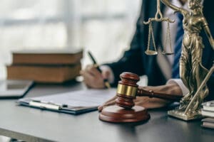 A desk with a judges gavel and small brass statue of 'Justice' holding her scales and a sword.