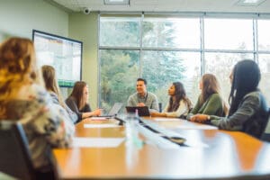 An experienced mentor offering advice and mentorship to a group of interns in a light-filled office training room, the mentorship moment captured with authenticity and empathy.