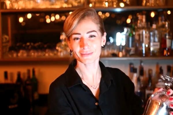 Friendly Female Bartender Smiling and Serving a Drink in a Cozy Bar Setting. Woman in bar.